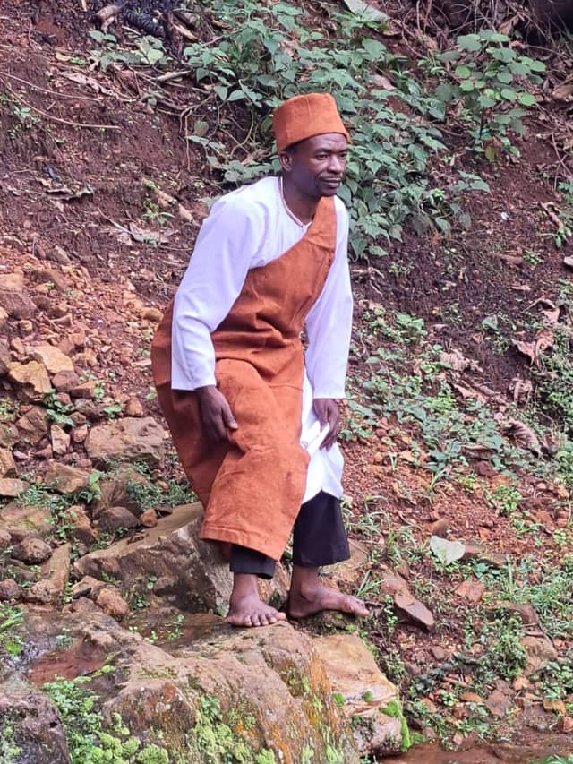 Person in bark cloth standing at the rocky cave entrance