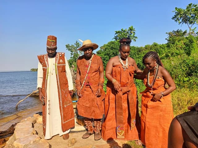 Four women in bark cloth standing on the shore