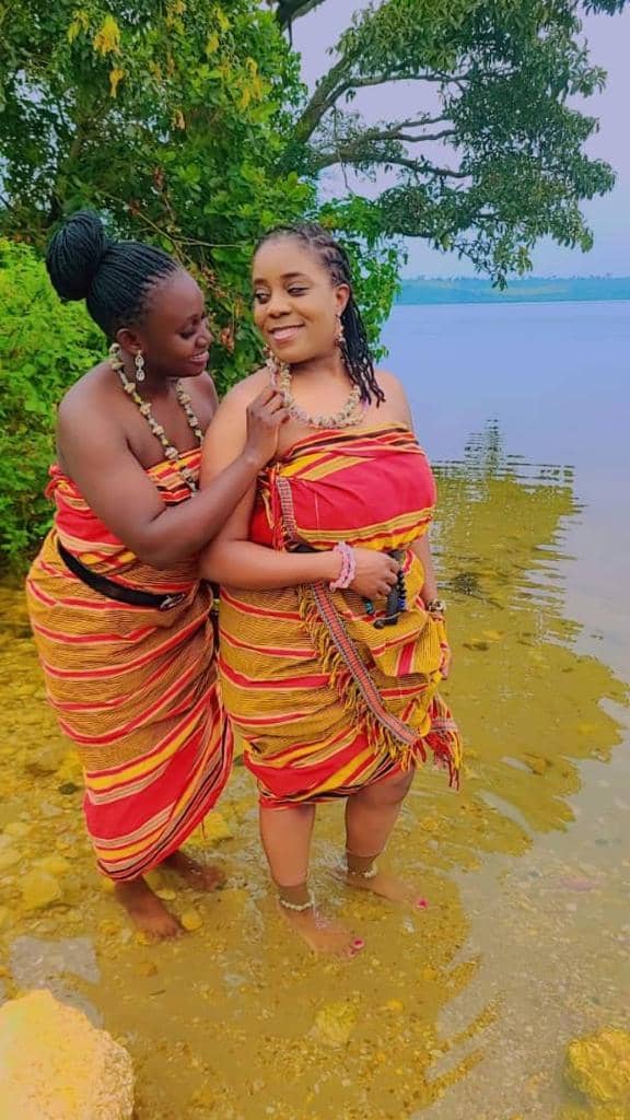 Two women in kente cloth standing on the shore