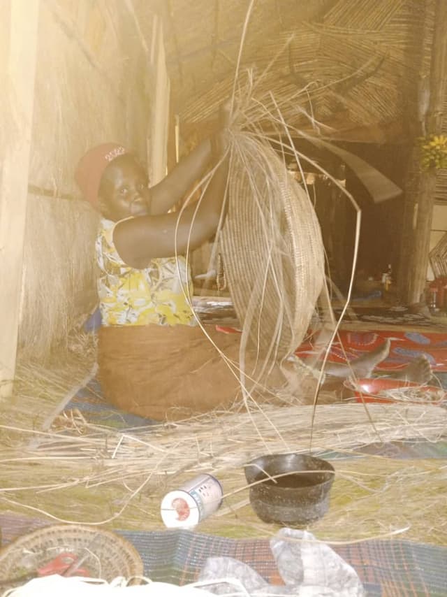 Woman weaving a large basket from natural fibres