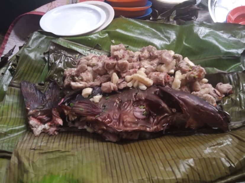 Chopped raw fish laid on a banana leaf, ready to cook
