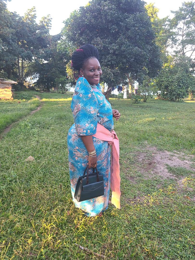 Queen Nalubaale walking through the compound in blue wax print