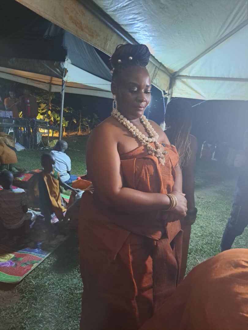 Queen Nalubaale at night by the fire in bark cloth and cowrie